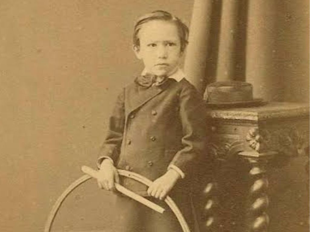 Black and white photograph of André Gide as a young child, aged 4, holding a hoop