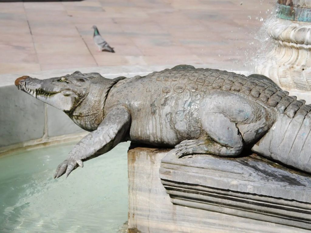 Bronze crocodile sculpture by artist Martial Raysse on the fountain of Place du Marché in Nîmes, symbol of the city