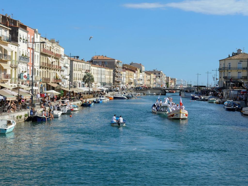 Colorful wooden jousting boats on Sète's Grand Canal lined with café terraces