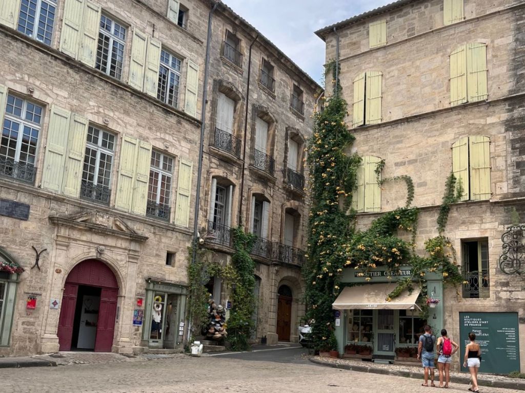 Historic square in Pézenas old town, lined with townhouse facades and wooden shutters