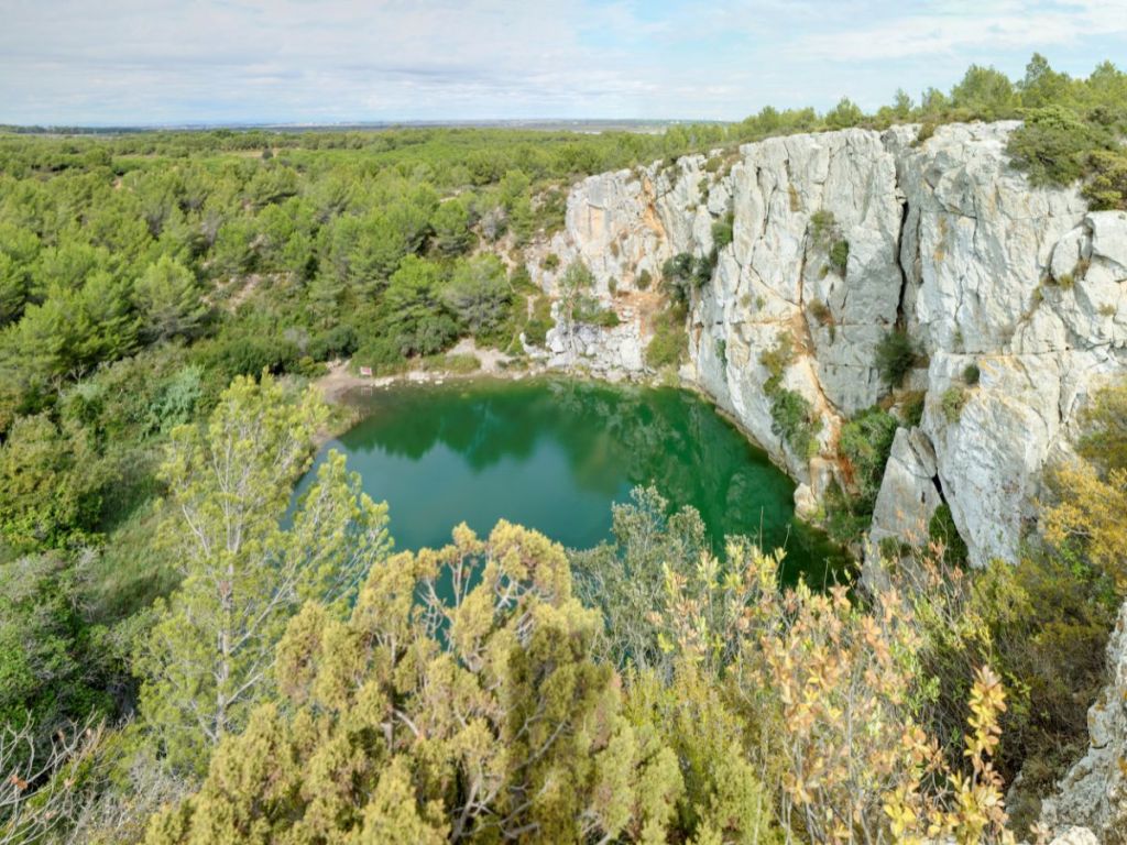 High-angle landscape view of the Gouffre de l'Œil Doux, in La Clape, Aude, France, with limestone cliffs and pine forests